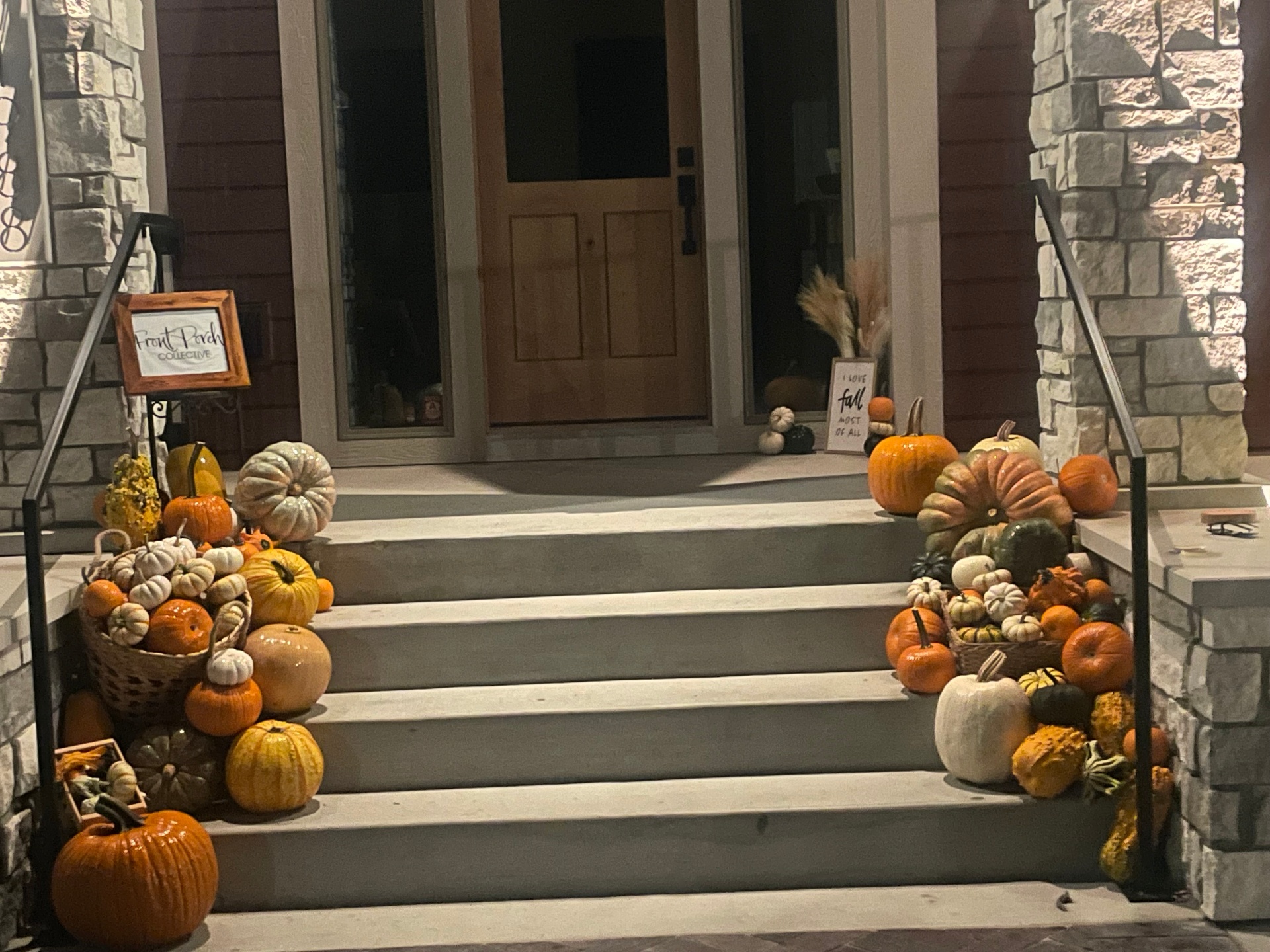 Professional fall porch decorating in Des Moines Iowa: heirloom pumpkins lining stone entry steps at dusk