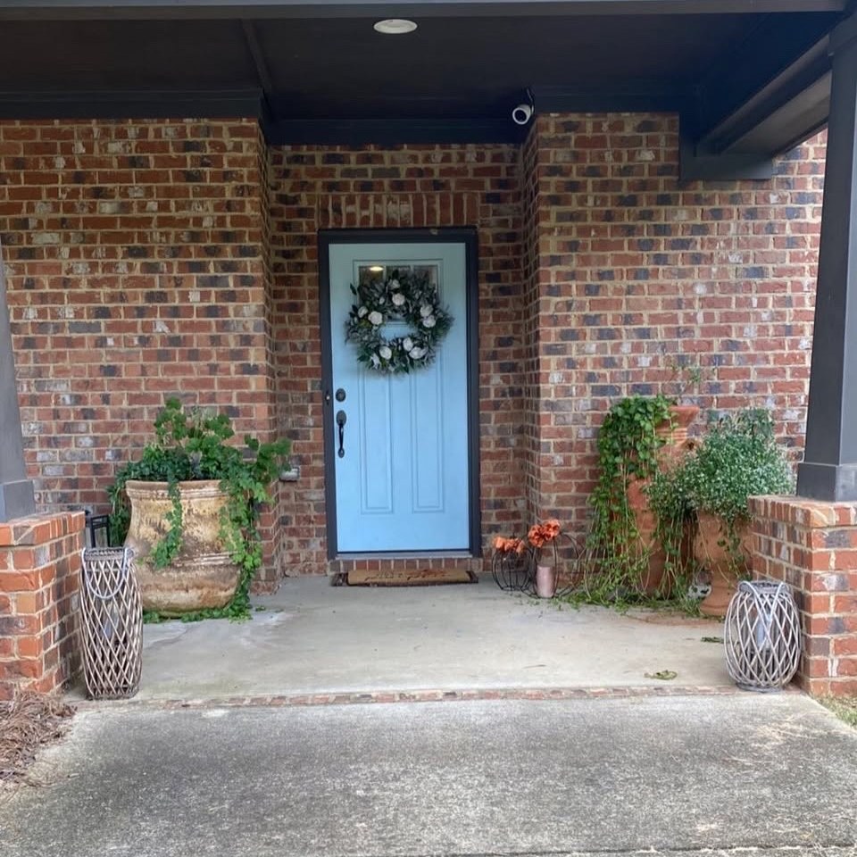 Before: bare red brick front porch with a light blue door